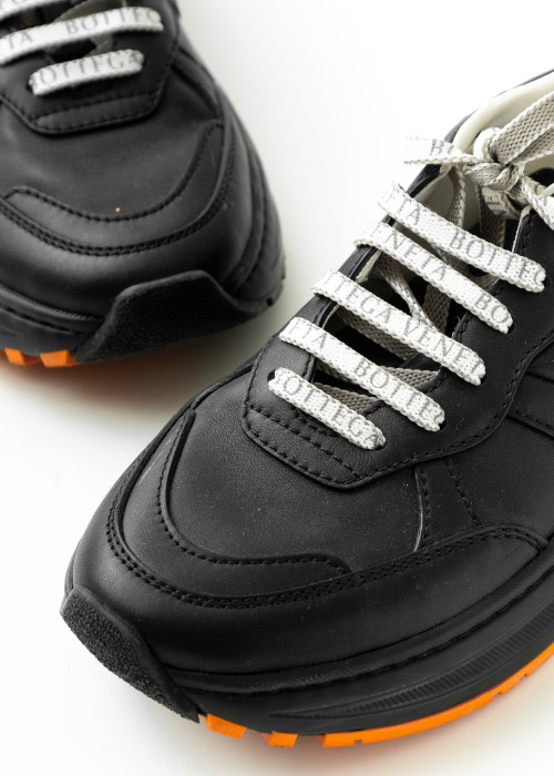Schwarze Sneakers mit orangefarbener Sohle