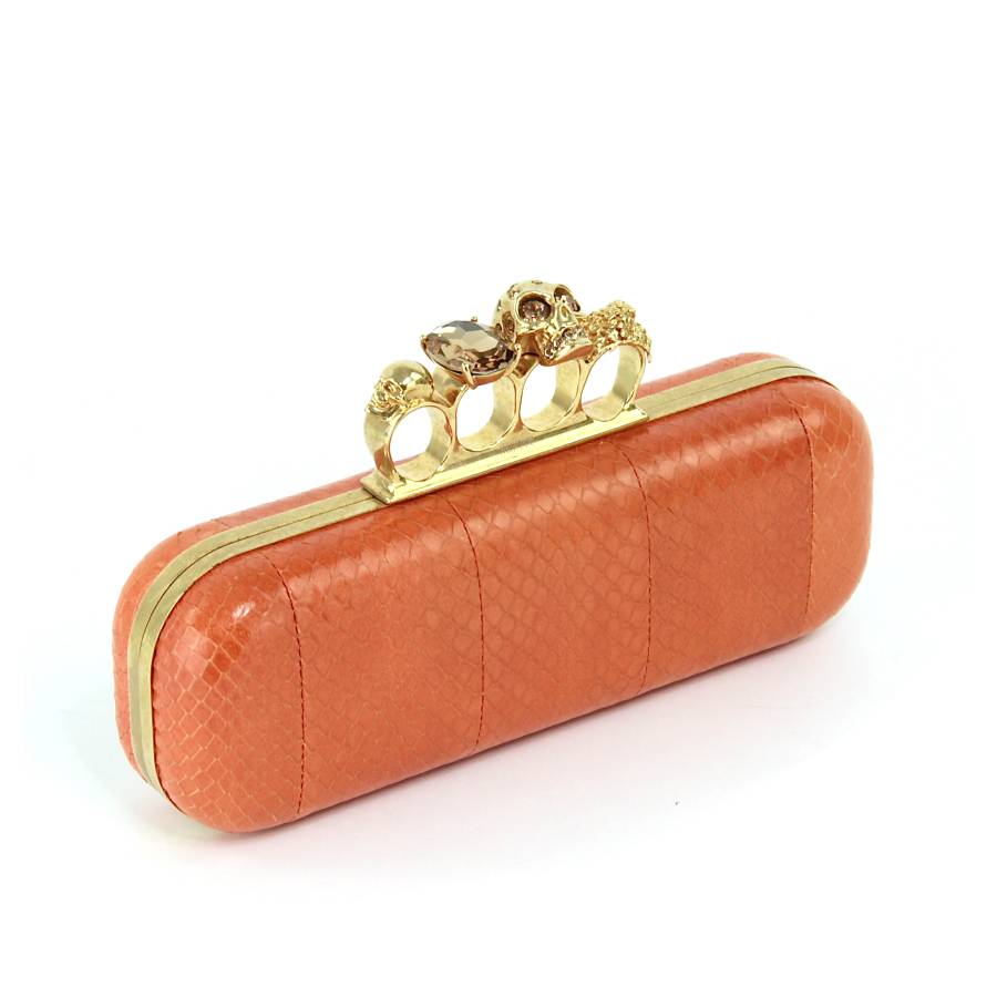 Orange leather clutch bag with gold jewellery