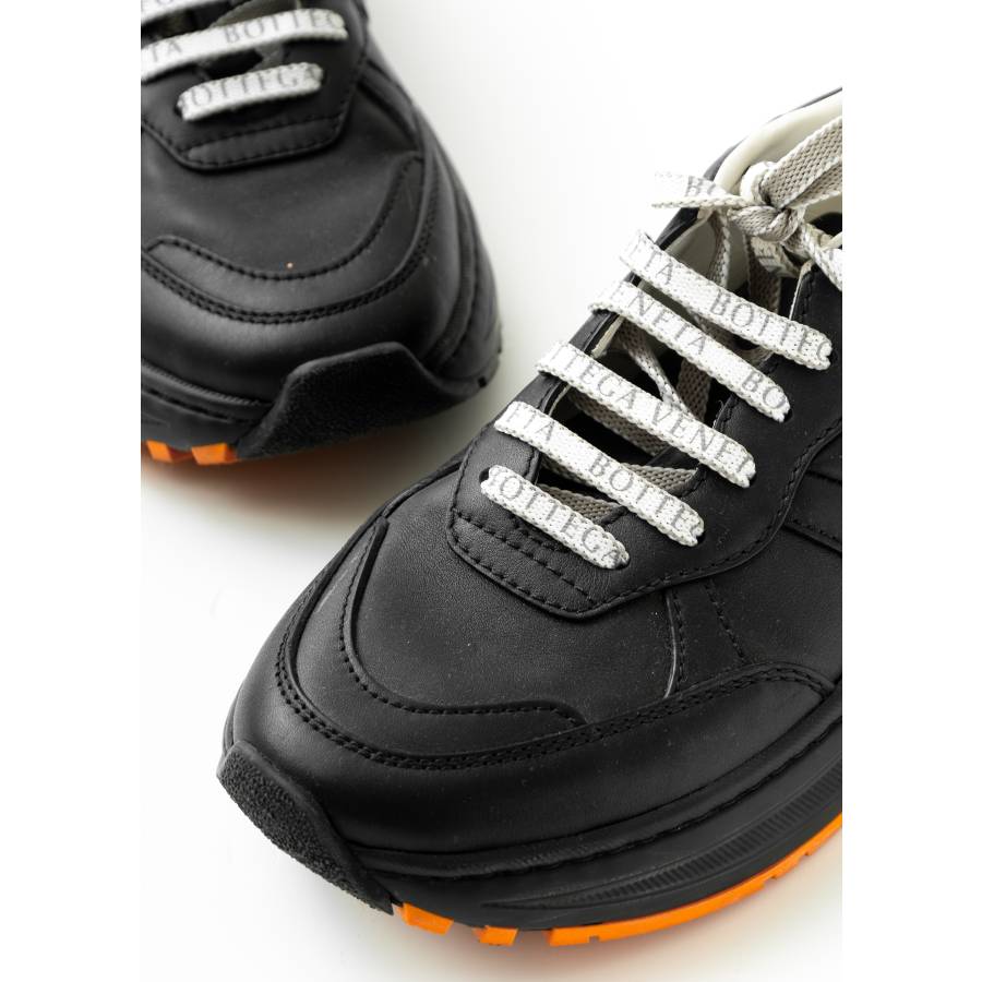 Black sneakers with orange sole