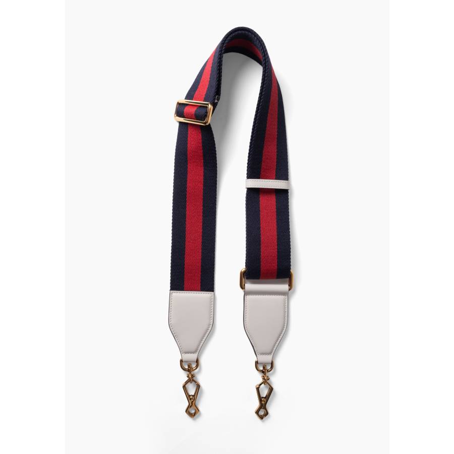 Bandoulière en toile Web avec des détails en cuir blanc et une quincaillerie dorée.